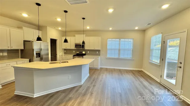 a large kitchen with stainless steel appliances kitchen island a large counter top and a wooden floors
