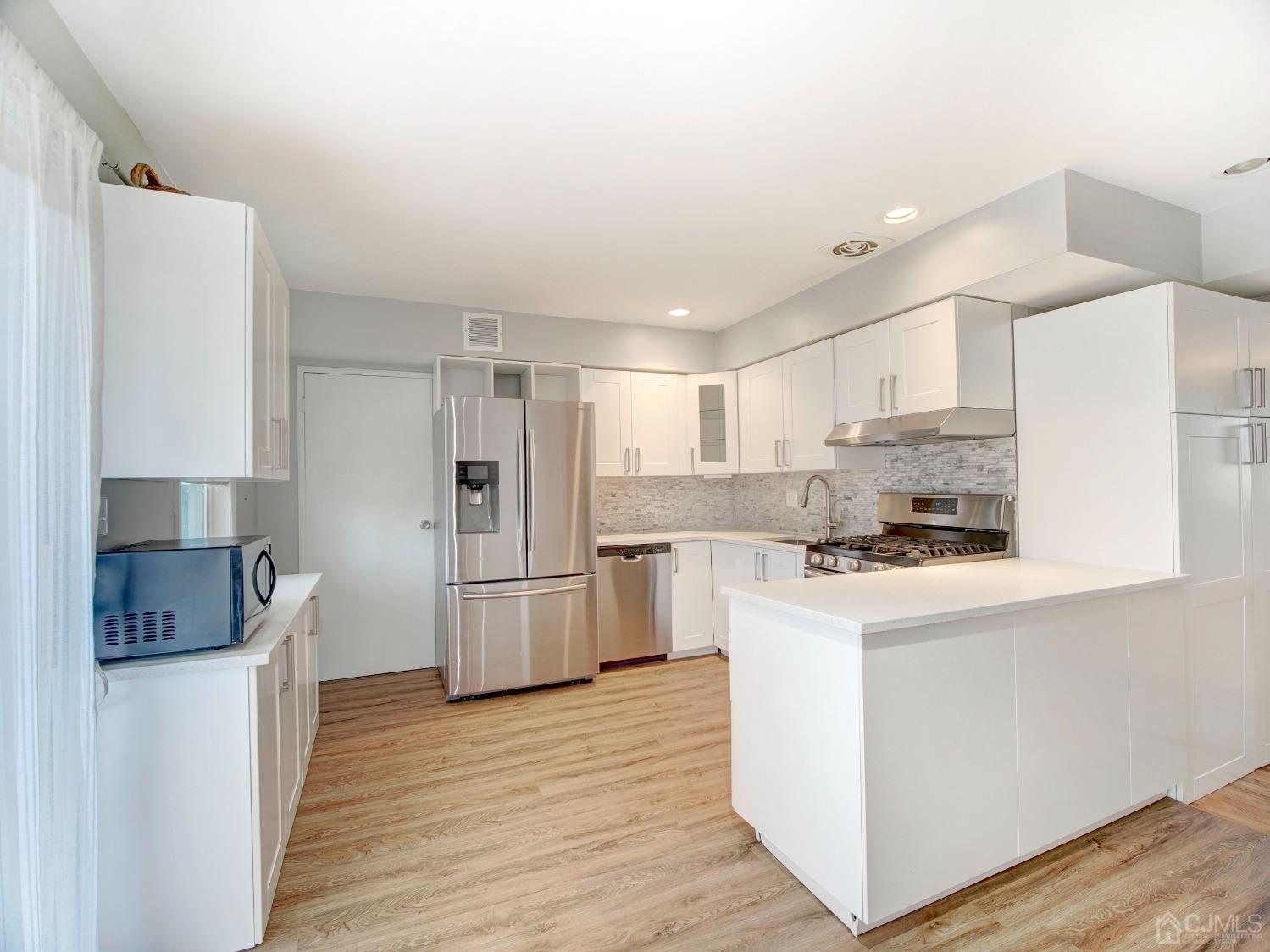 57 Judson Street, Unit 10B Edison, NJ 08837 - Photo 8 of 25 a kitchen with stainless steel appliances a refrigerator stove a sink and white cabinets with wooden floor