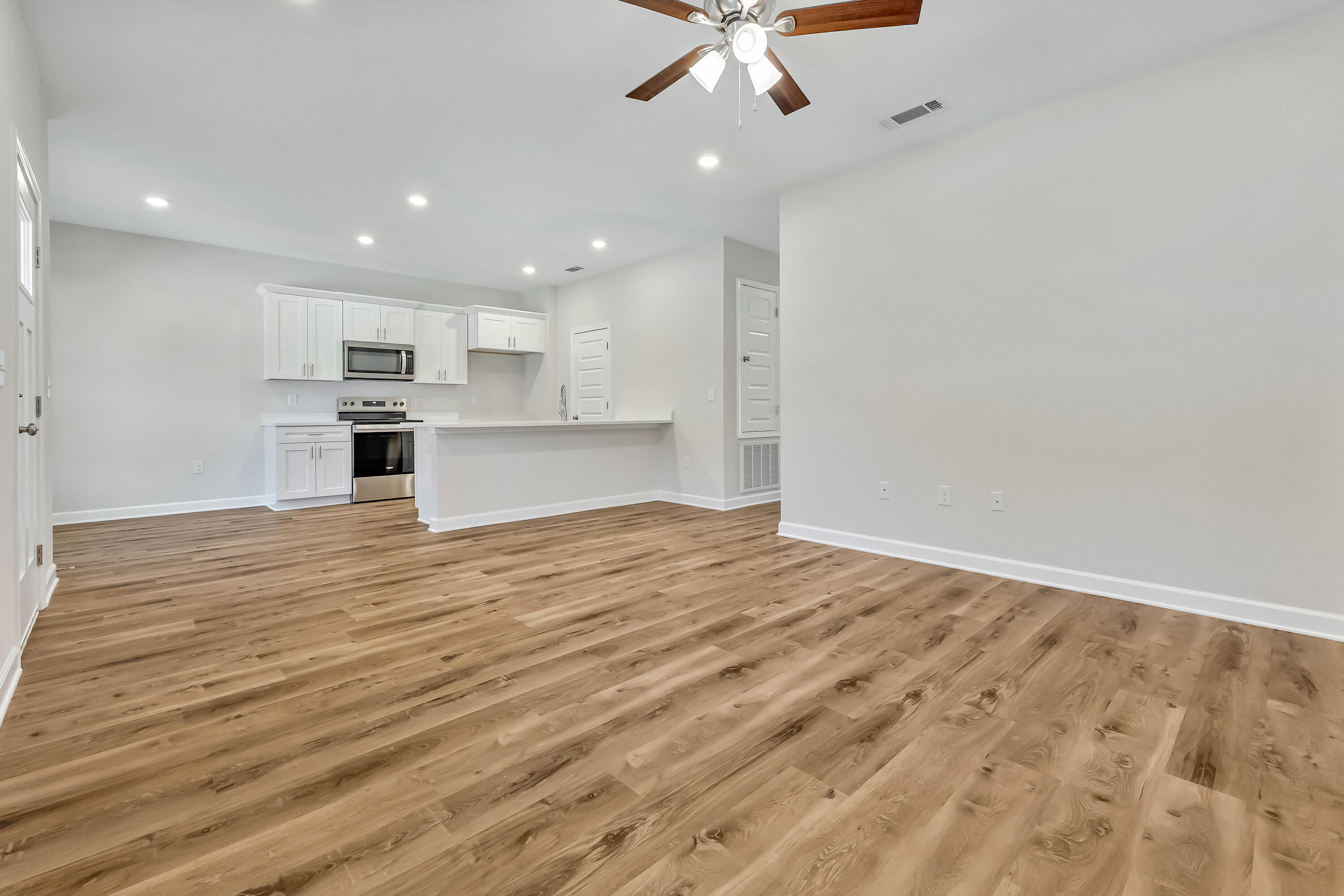 593 Brock Avenue Crestview, FL 32539 - Photo 6 of 19 wooden floor in an empty room with kitchen view