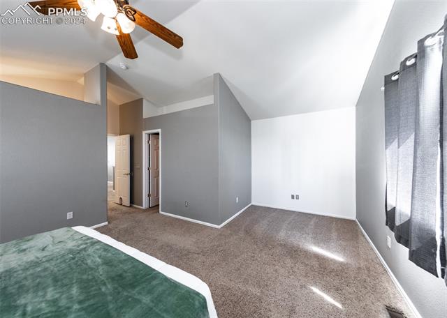 995 Winebrook Way Fountain, CO 80817 - Photo 24 of 44 Unfurnished bedroom with ceiling fan, dark carpet, and lofted ceiling