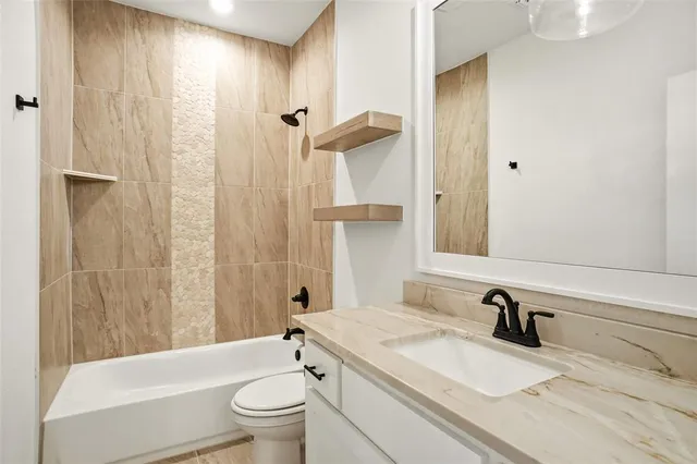 a bathroom with a granite countertop sink a toilet and a mirror
