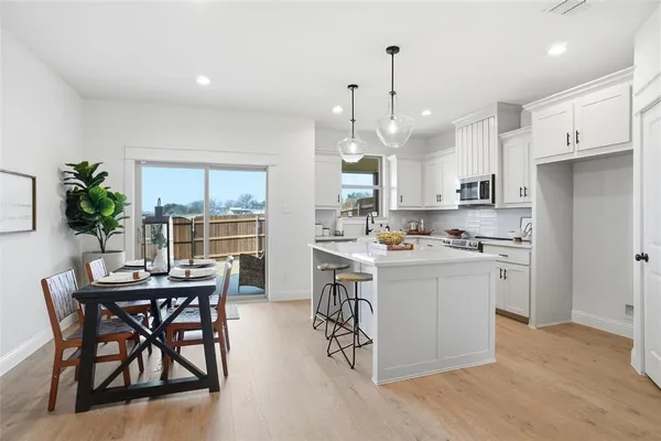 a kitchen with a table chairs refrigerator and microwave