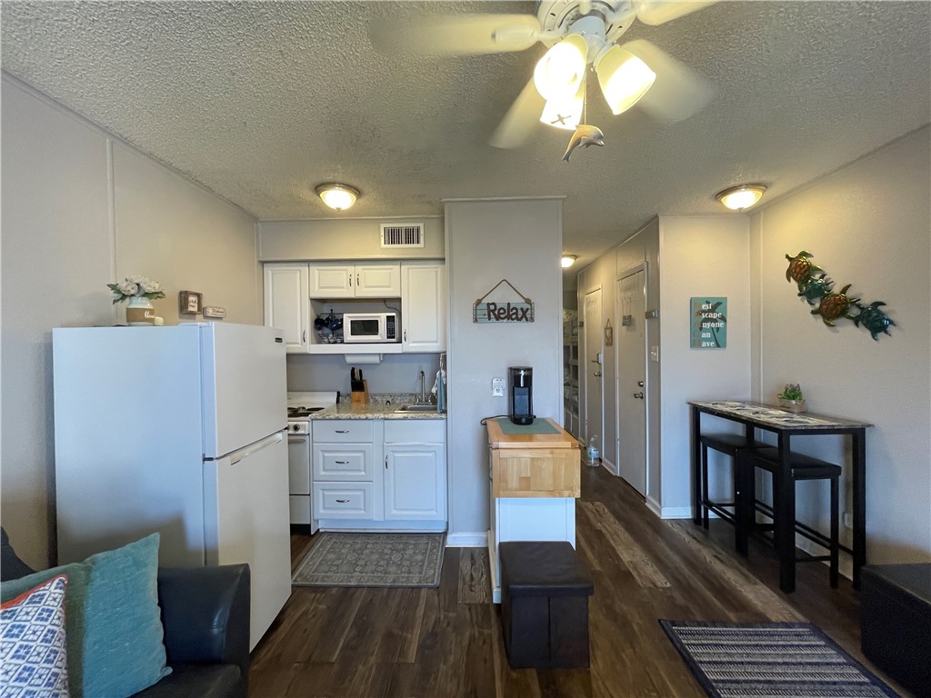 3938 Surfside Boulevard, Unit 3344 Corpus Christi, TX 78402 - Photo 15 of 34 a kitchen with stainless steel appliances granite countertop a refrigerator a stove a sink dishwasher and a dining table with wooden floor
