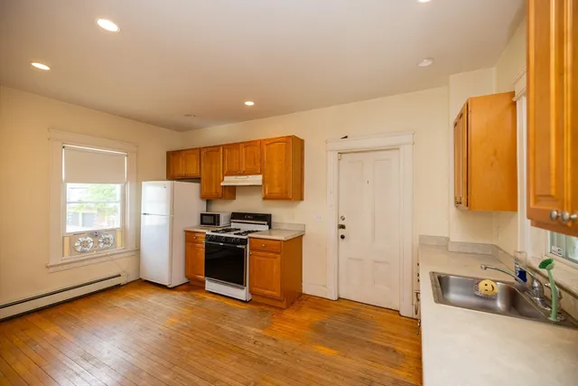 a kitchen with stainless steel appliances granite countertop a stove a sink and a refrigerator with wooden floors