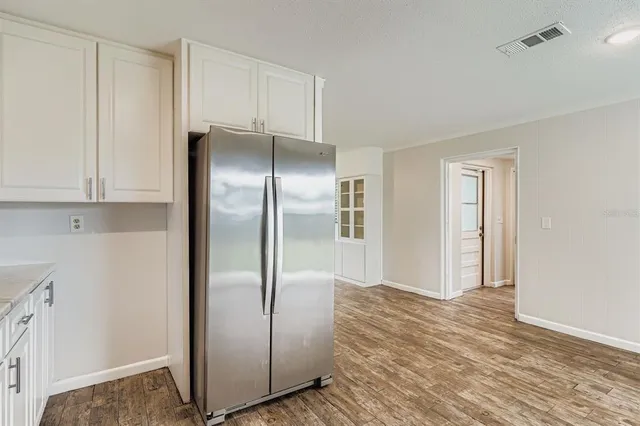 a view of a refrigerator in kitchen and white cabinets