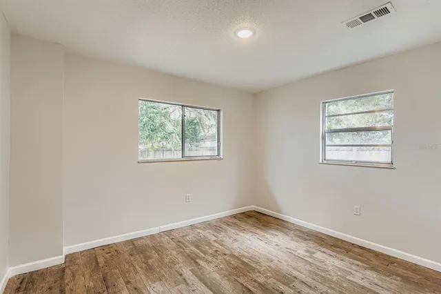 an empty room with wooden floor and windows