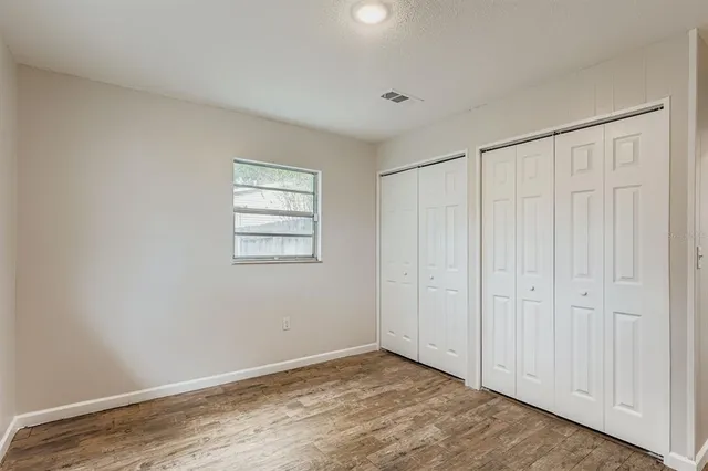 a view of an empty room with closet and a window