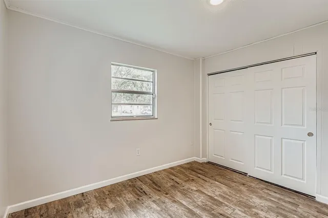 a view of an empty room with wooden floor and closet
