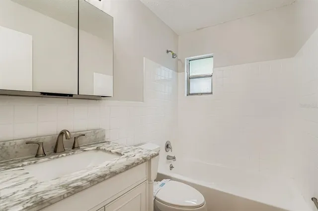 a bathroom with a granite countertop sink toilet and mirror