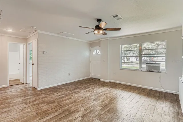 a view of empty room with wooden floor and fan