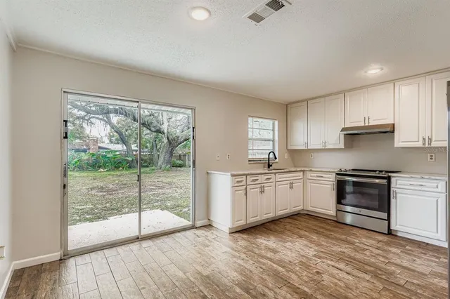 a kitchen with granite countertop a stove top oven sink and cabinets
