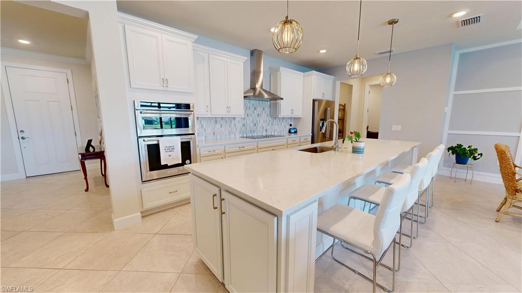 6162 Nobility Way Avenue Immokalee, FL 34142 - Photo 7 of 50 a kitchen with kitchen island a stove a table and chairs in it