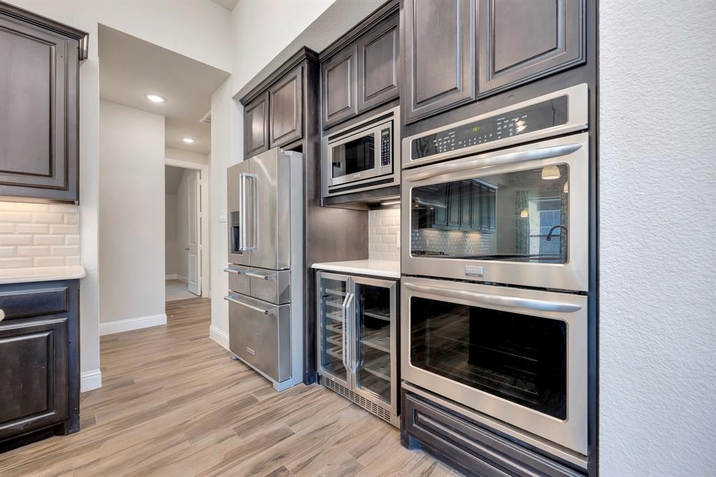 9820 Surveyor Road Little Elm, TX 75068 - Photo 10 of 40 Kitchen with appliances with stainless steel finishes, wine cooler, decorative backsplash, recessed lighting, and light wood finished floors