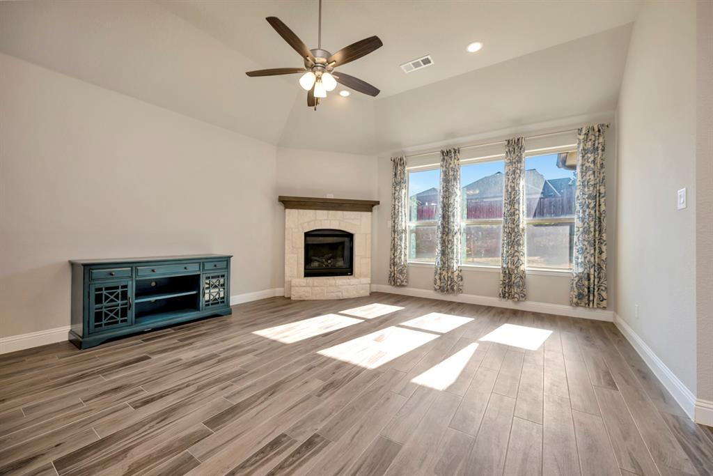 9820 Surveyor Road Little Elm, TX 75068 - Photo 7 of 40 Unfurnished living room with a fireplace with raised hearth, wood finish floors, a ceiling fan, recessed lighting, and vaulted ceiling