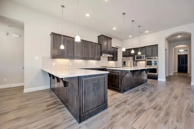 a kitchen with kitchen island granite countertop a sink and a refrigerator