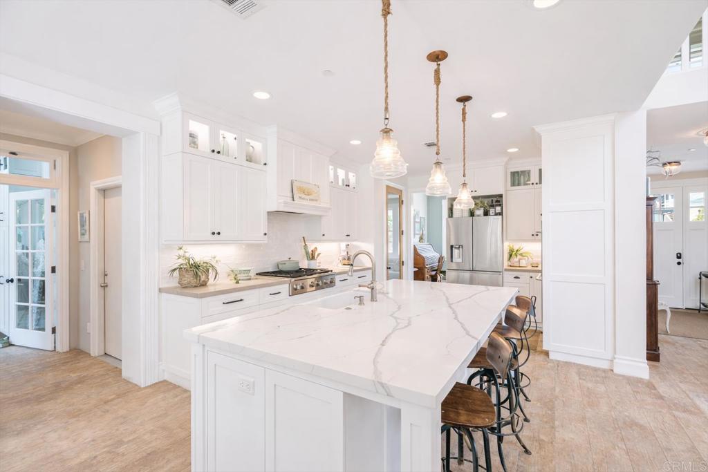 162 Jupiter Street Encinitas, CA 92024 - Photo 7 of 31 a kitchen with stainless steel appliances kitchen island granite countertop a stove a sink a refrigerator and a dining table with wooden floor