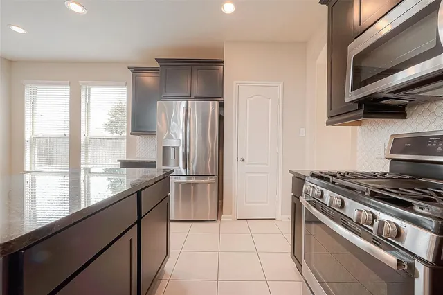 a kitchen with stainless steel appliances granite countertop a stove a refrigerator and a microwave