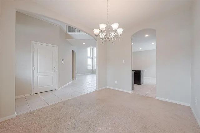 a view of an empty room with a chandelier fan