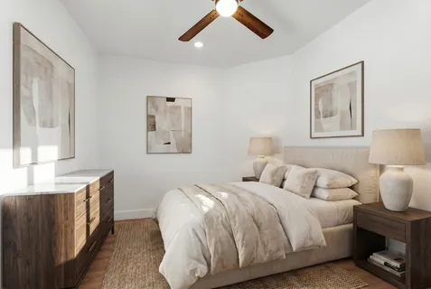 a bedroom with a bed and a lamp on dresser with a large window