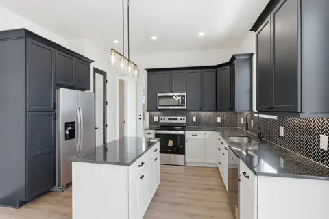 a kitchen with stainless steel appliances granite countertop a refrigerator a stove a sink and a microwave
