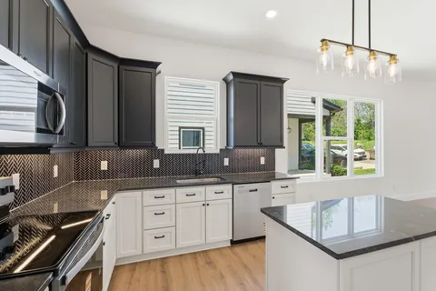a kitchen with granite countertop a sink a stove and cabinets