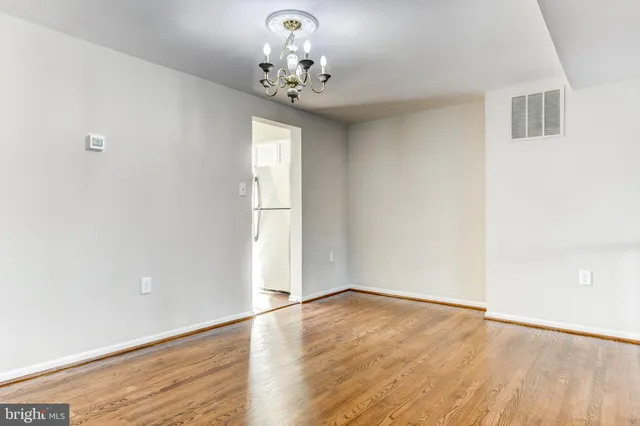 an empty room with wooden floor and chandelier