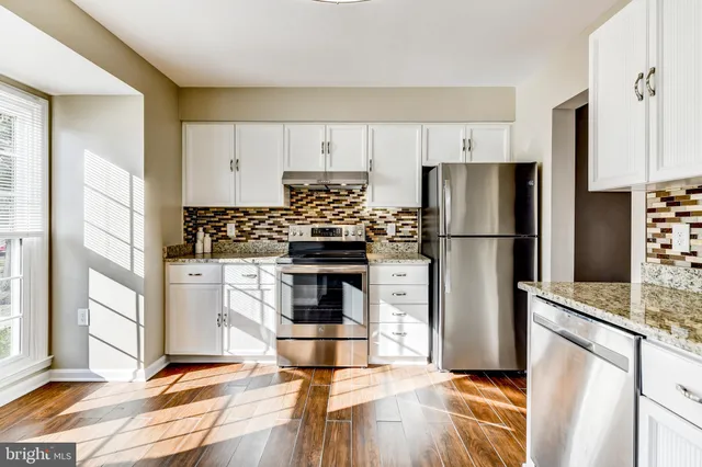 a kitchen with granite countertop a refrigerator and a stove top oven