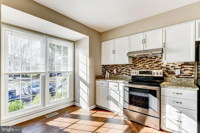 a kitchen with stainless steel appliances a stove and white cabinets
