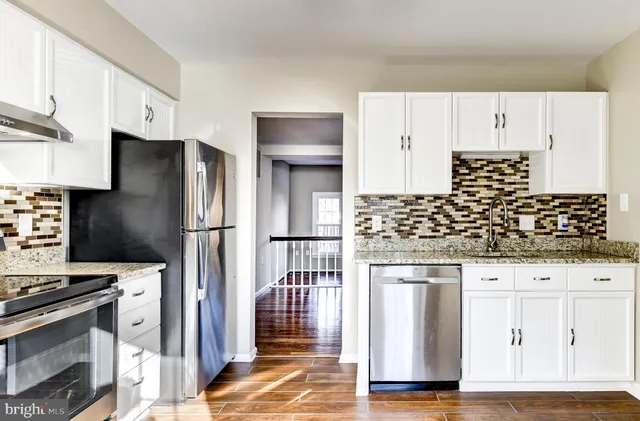 a kitchen with granite countertop white cabinets and stainless steel appliances
