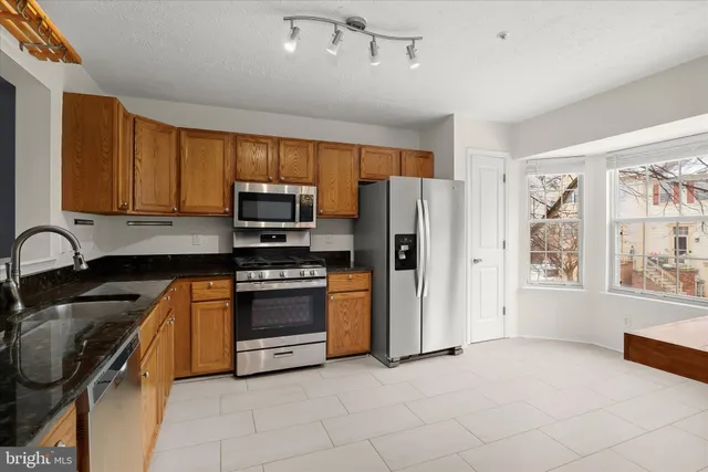 a kitchen with stainless steel appliances granite countertop a stove a sink and a refrigerator