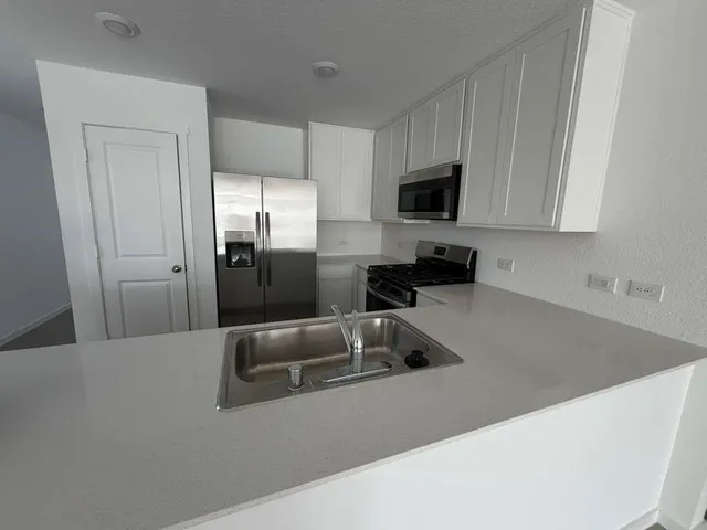 a kitchen with stainless steel appliances granite countertop a sink a refrigerator and a granite counter tops