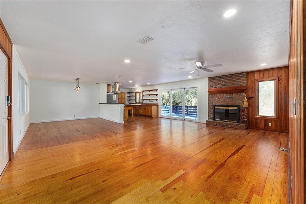 22157 Northwest 87th Avenue Road Micanopy, FL 32667 - Photo 4 of 34 a view of empty room with wooden floor and a fireplace