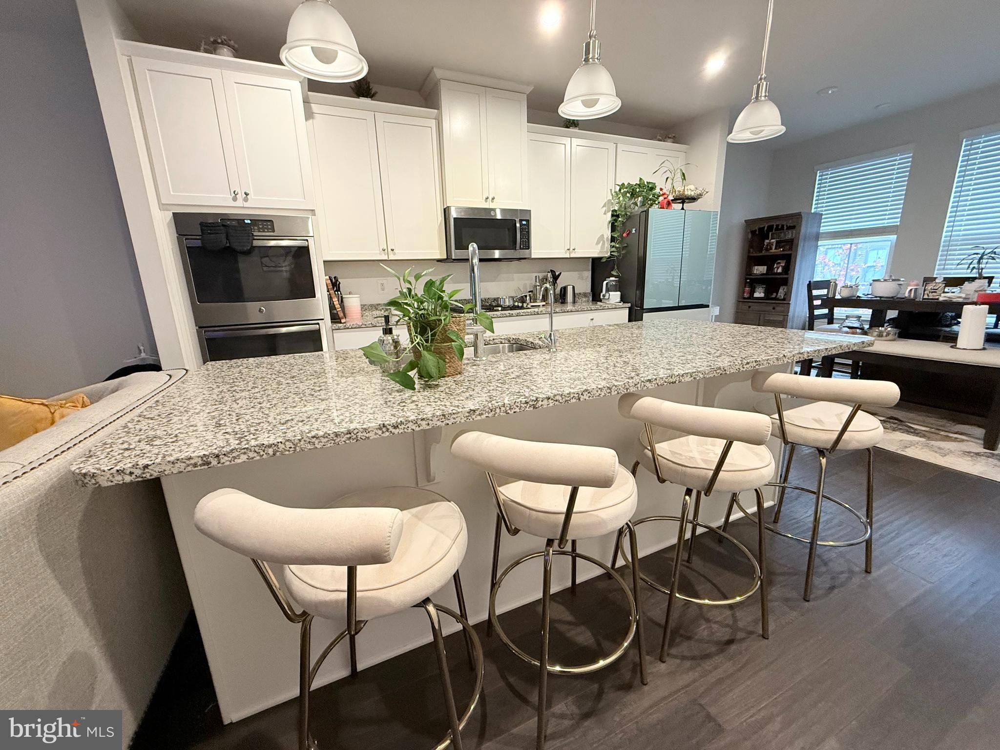 22269 Sims Terrace Ashburn, VA 20148 - Photo 12 of 44 a kitchen with stainless steel appliances kitchen island granite countertop a dining table chairs and a refrigerator