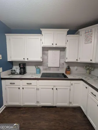 a white kitchen with granite countertop white cabinets and a sink