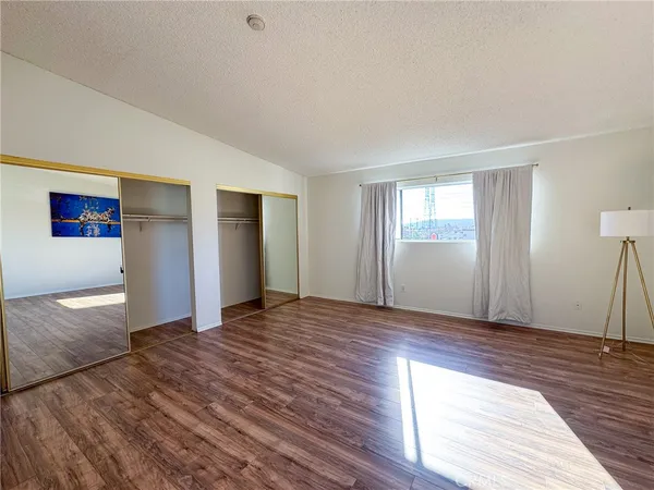 a view of an empty room with window and wooden floor