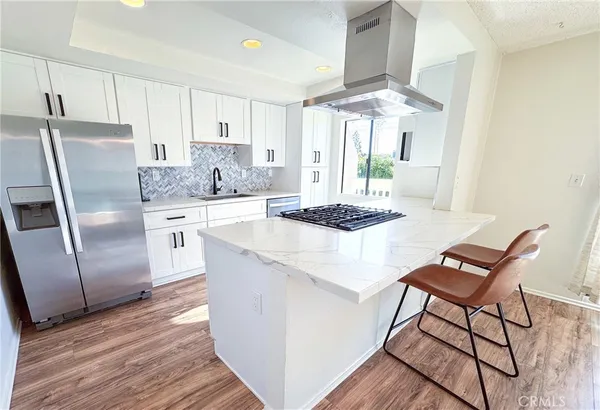a kitchen with stainless steel appliances a dining table chairs and refrigerator