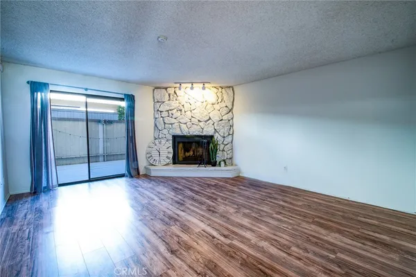 an empty room with wooden floor fireplace and windows