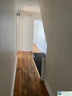 a view of a hallway with wooden floor and white walls