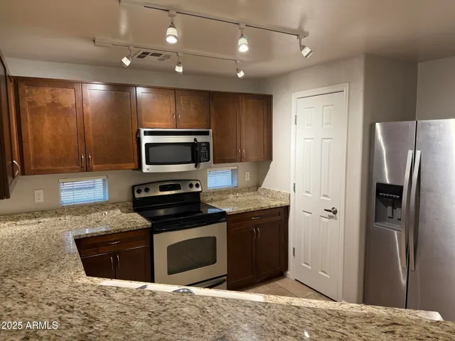 a kitchen with stainless steel appliances granite countertop a refrigerator a stove a sink and a microwave