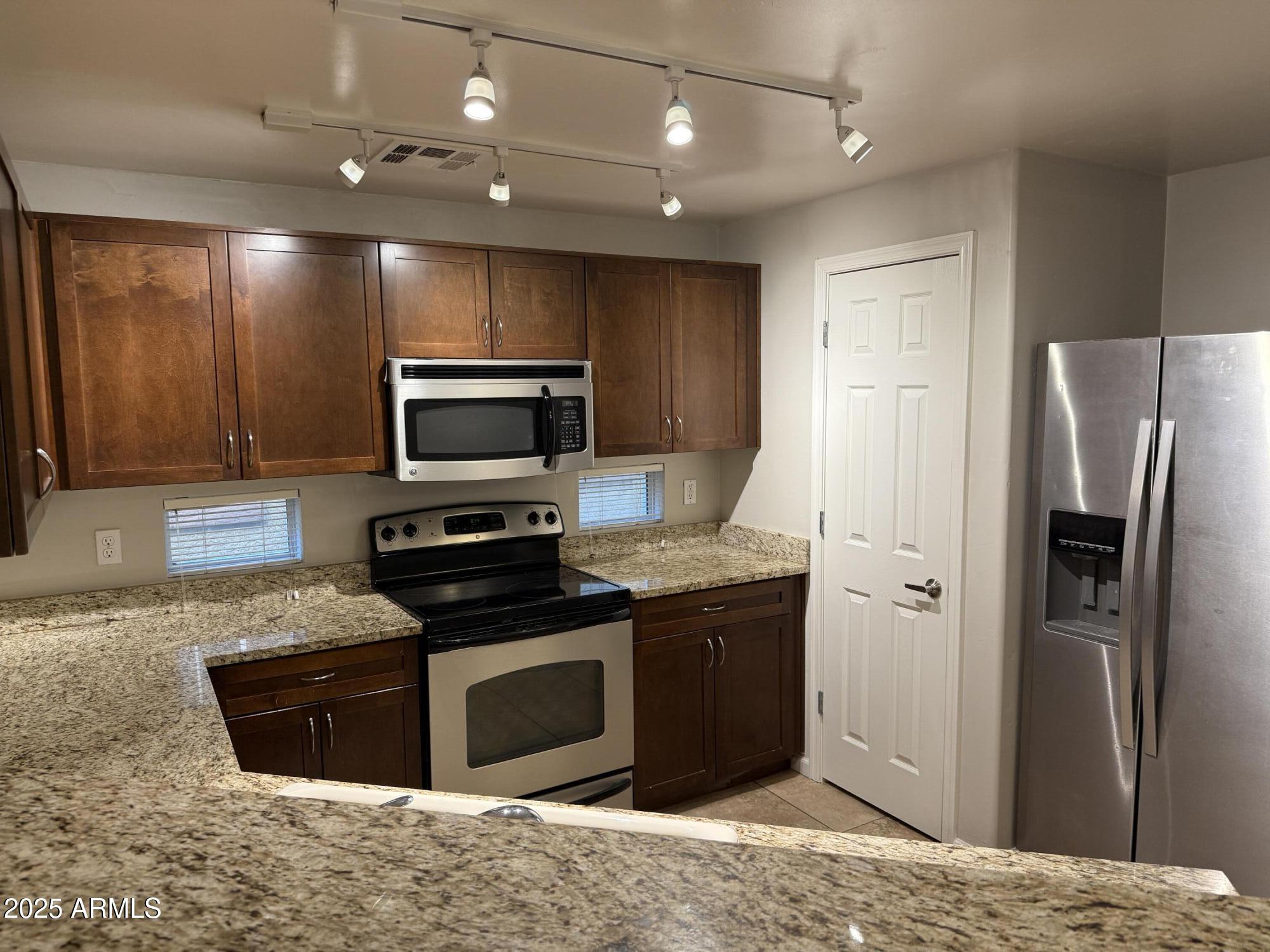 1920 East Bell Road, Unit 1149 Phoenix, AZ 85022 - Photo 13 of 33 a kitchen with stainless steel appliances granite countertop a refrigerator a stove a sink and a microwave