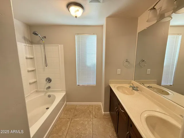 a bathroom with a granite countertop tub sink a mirror and a shower