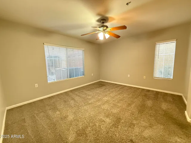 a view of an empty room with chandelier fan and a window