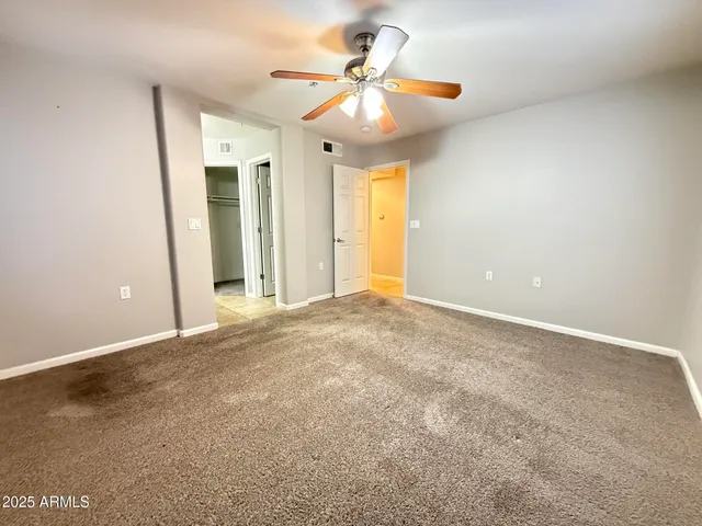an empty room with a ceiling fan and window