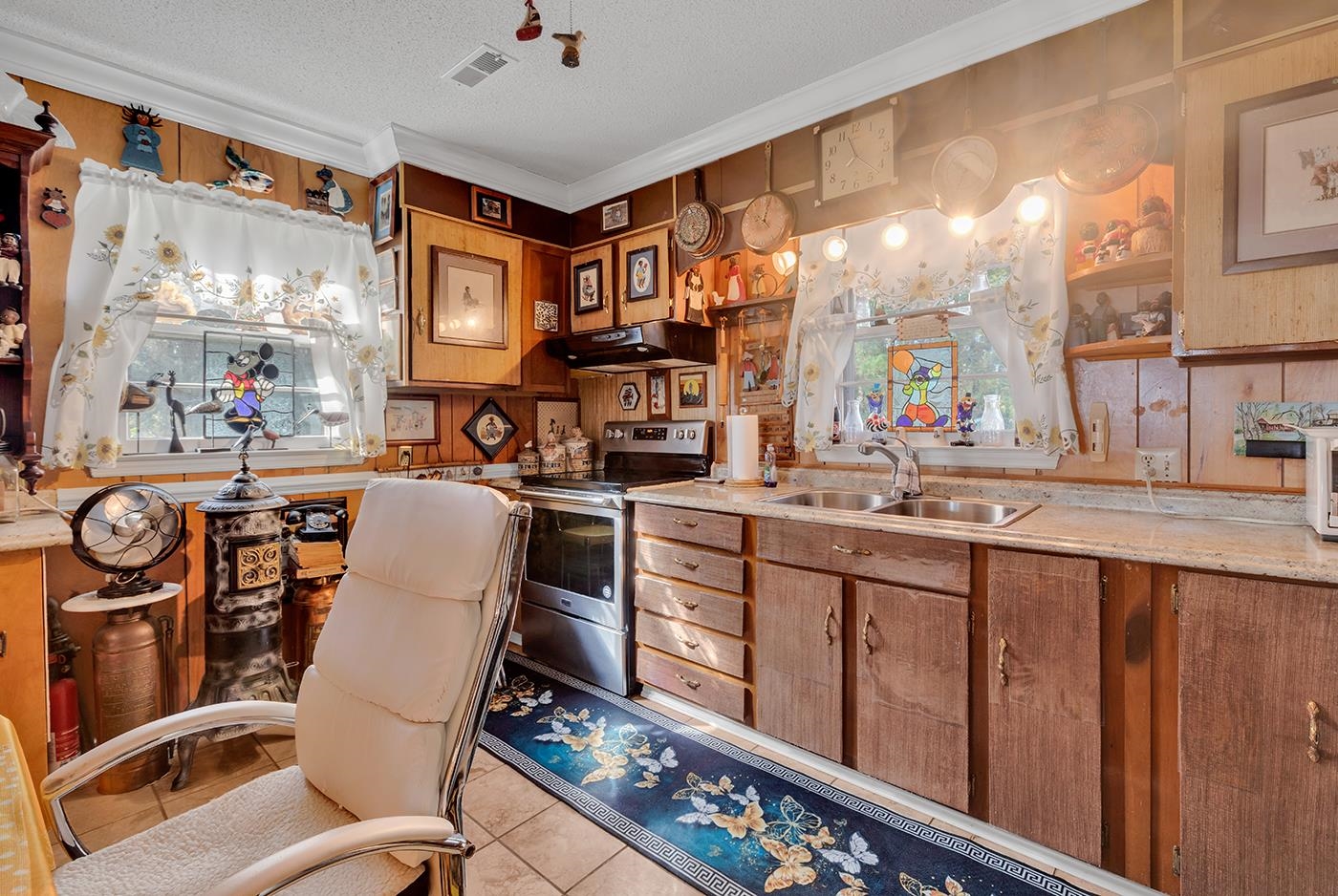 2023 Asbury Street Georgetown, SC 29440 - Photo 12 of 40 Kitchen featuring electric stove, light countertops, under cabinet range hood, crown molding, and brown cabinets