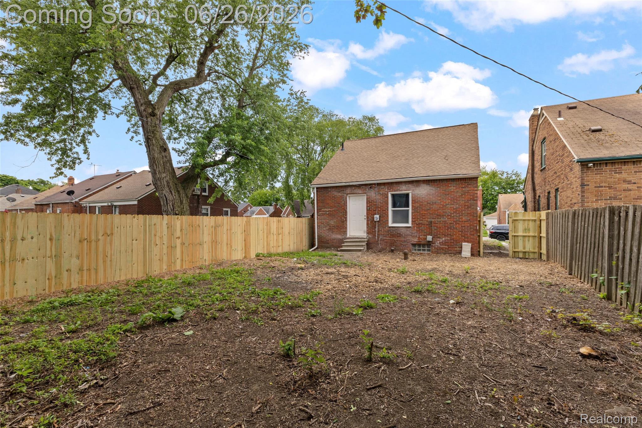 8310 Whitcomb Detroit, MI 48228 - Photo 6 of 26 Spacious rear yard featuring a newly installed privacy fence, an established mature tree, and a brick exterior structure