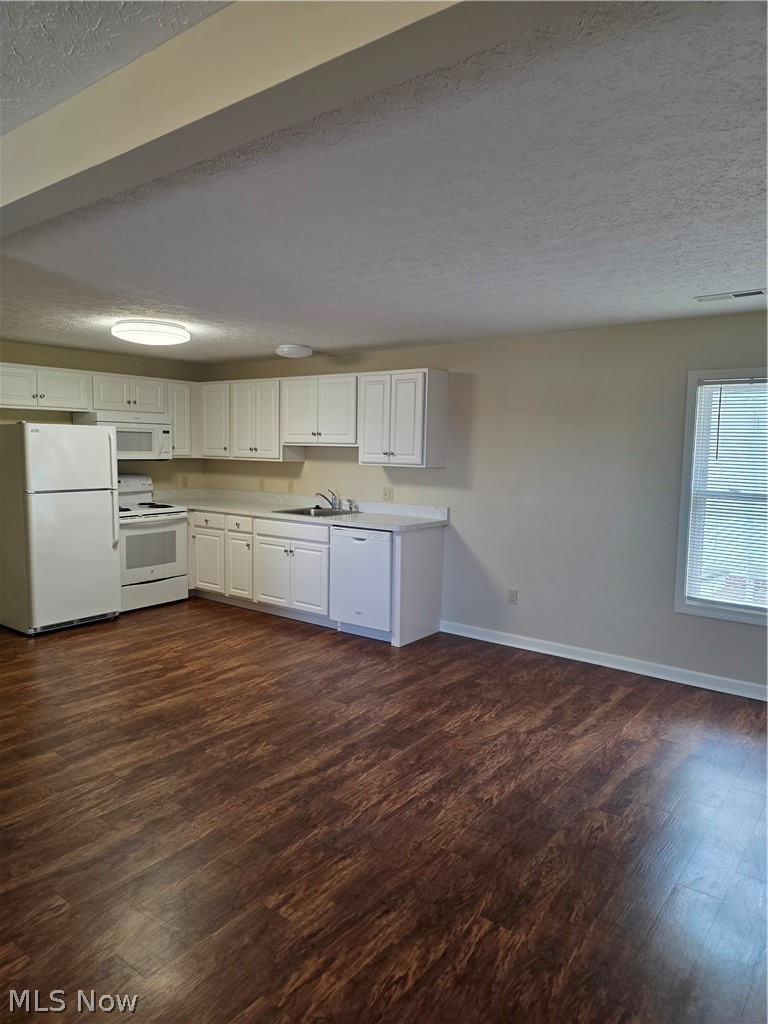 9889 Johnnycake Ridge Road, Unit B Mentor, OH 44060 - Photo 2 of 7 Open-concept living space with wood-finish flooring, white cabinetry, integrated kitchen appliances, and natural light from a prominent window