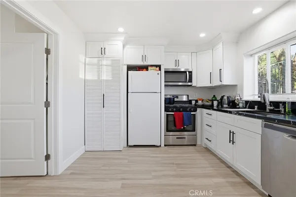 a kitchen with stainless steel appliances granite countertop a sink a stove a dining table and chairs