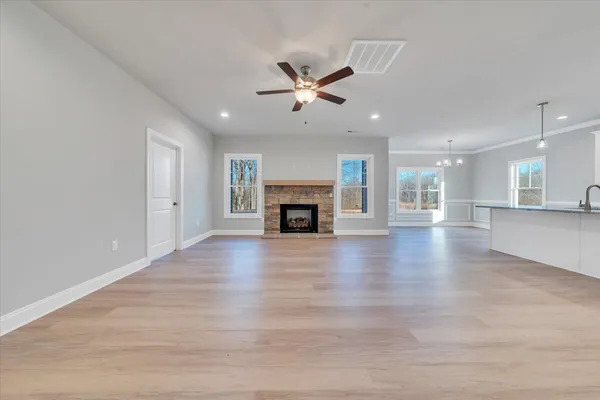 an empty room with wooden floor fireplace and windows