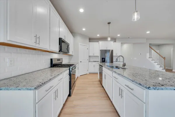 a large kitchen with stainless steel appliances kitchen island a large counter top a stove and a sink