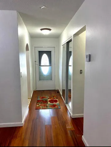 a view of an empty room with wooden floor and a mirror